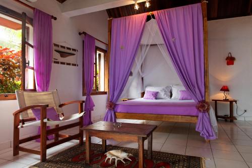 a bedroom with a canopy bed with purple curtains at Hotel Vanivola & SPA in Sainte Marie
