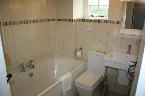 a bathroom with a tub and a toilet and a sink at The Rectory Lacock Cottages in Lacock