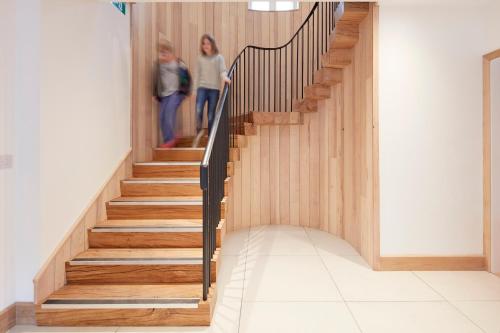 two women walking down a wooden staircase in a house at The Barrel Store Cirencester in Cirencester