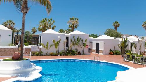 a pool in front of a house with palm trees at Los Cardones Boutique Village in Playa de las Americas