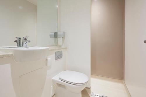 a white bathroom with a toilet and a sink at The Barrel Store Cirencester in Cirencester
