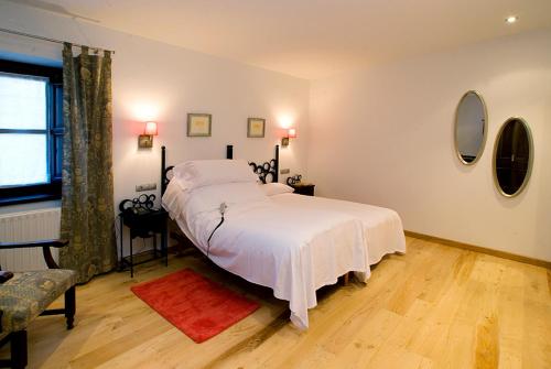 a bedroom with a large bed with white sheets at Hotel y apartamentos rurales L'Anceo in Cibuyo