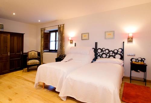 a bedroom with two beds with white sheets and a chair at Hotel rural L'Anceo in Cibuyo