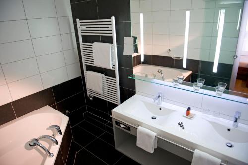 a bathroom with two sinks and a mirror at Hotel Quellenhof Leukerbad in Leukerbad
