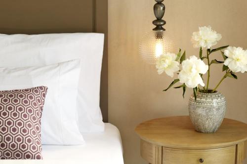a vase with white flowers on a table next to a bed at Nido, Mar-Bella Collection in Agios Ioannis Peristeron