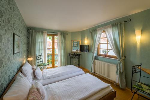 a bedroom with two beds and two windows at Landhotel Kallstadt in Kallstadt