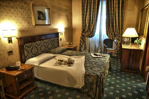 una habitación de hotel con una cama grande y una mesa en Hotel Cilicia en Roma