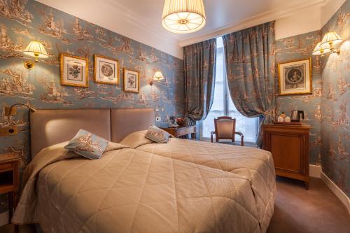 a bedroom with a bed with blue wallpaper at Grand Hôtel de L'Univers Saint-Germain in Paris