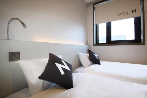 a bedroom with two beds with black and white pillows at Seoul N Guesthouse Dongdaemoon in Seoul