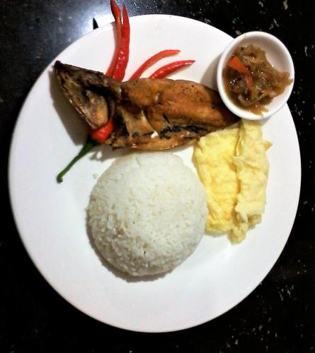 a plate of food with rice and fish and a bowl of sauce at Fj Manila Hotel in Daraga