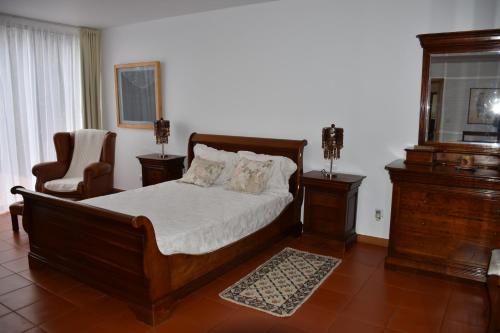 a bedroom with a wooden bed and a chair at Caloura Camellia House in Caloura