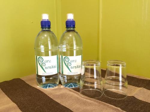 two bottles of water and two glasses on a table at Parakai Geothermal Motel in Parakai