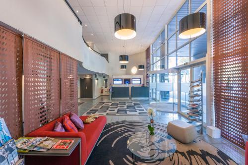 an office lobby with a red couch and a table at Hotel Mercure Grenoble Centre Président in Grenoble