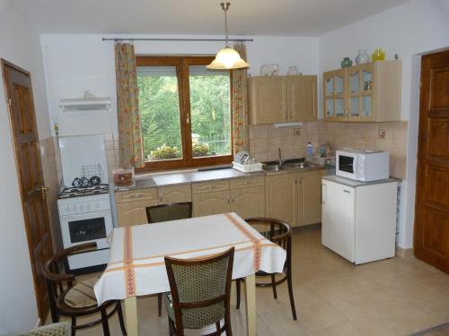 a kitchen with a table and a white refrigerator at Gyümölcsöskert Szálláshely in Debrecen