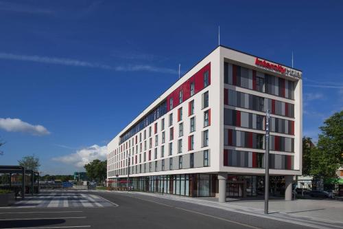 a large white building with red windows on a street at IntercityHotel Duisburg in Duisburg