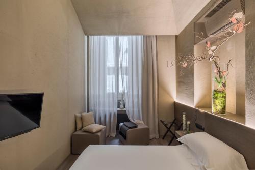 a bedroom with a bed and a chair and a window at Hotel dei Barbieri in Rome
