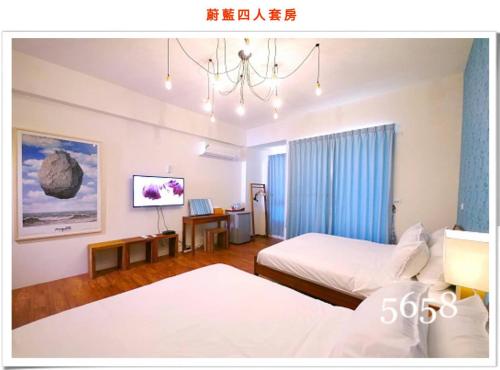 a hotel room with two beds and a chandelier at 蔚藍白鷺民宿 in Donggang