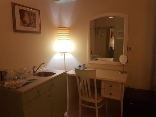 a bathroom with a sink and a lamp and a mirror at Yiannis Apartments in Ioannina