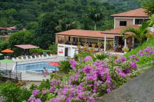 a view of a resort with a pool and flowers at Hotel La Montaña San Gil in San Gil