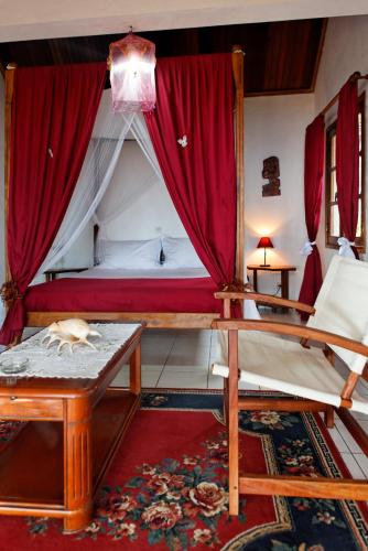 a bedroom with a canopy bed with a cat sleeping on a table at Hotel Vanivola & SPA in Sainte Marie