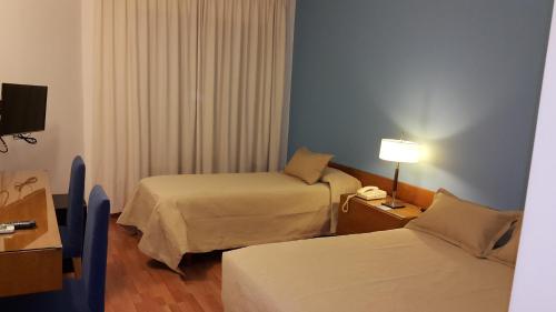 a hotel room with two beds and a lamp at Hotel Avenida in Buenos Aires