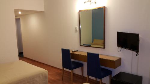 a room with a desk with two chairs and a mirror at Hotel Avenida in Buenos Aires