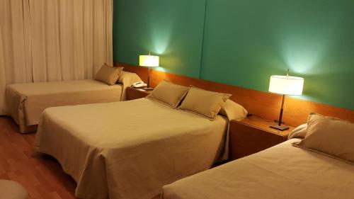 a hotel room with two beds and a green wall at Hotel Avenida in Buenos Aires