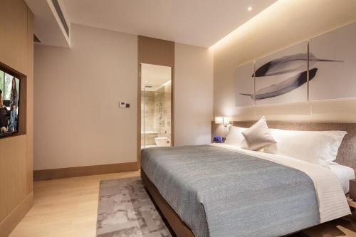 a bedroom with a large bed and a painting on the wall at Ascott Raffles City Shenzhen in Shenzhen