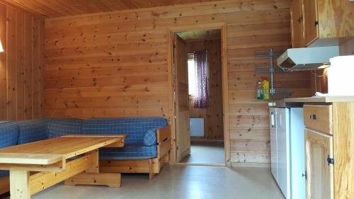 Cabaña de madera con sala de estar con sofá azul y mesa. en Jotunheimen Feriesenter en Heidal