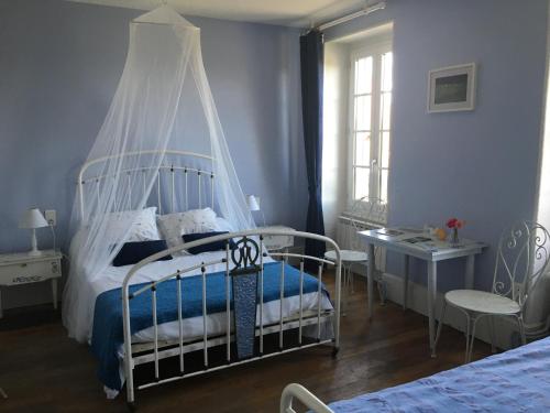 a bedroom with a white bed with a canopy at Chambres d'hôtes et Roulotte Au Bonheur Du Parc in Le Breuil