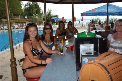 a group of women sitting at a table at the beach at Ahilea Hotel - Free Pool Access in Balchik