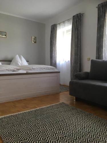 a bedroom with a bed and a couch and a window at Frühstückspension Scharinger Hof in Gilgenberg am Weilhart