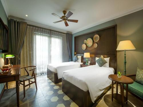 a hotel room with two beds and a couch at AIRA Boutique Hoi An Hotel & Villa in Hoi An