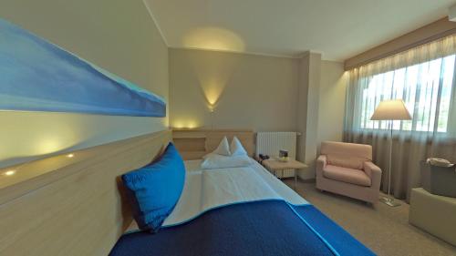 a hotel room with a large bed and a chair at Hotel Moserhof in Seeboden