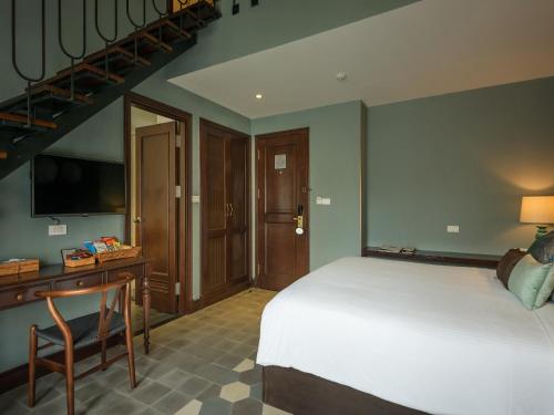 a bedroom with a bed and a desk and a television at AIRA Boutique Hoi An Hotel & Villa in Hoi An