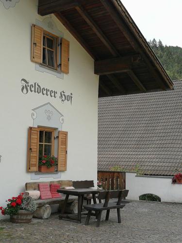 a patio with a table and a bench in front of a building at Feldererhof in Siusi