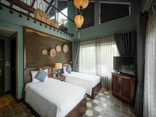 a hotel room with two beds and a flat screen tv at AIRA Boutique Hoi An Hotel & Villa in Hoi An