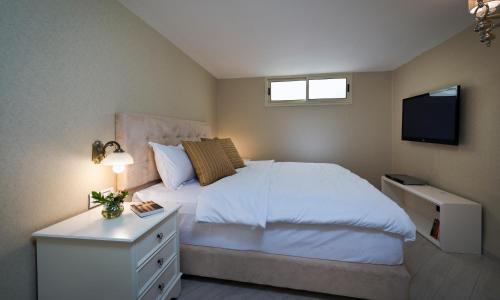 1 dormitorio con 1 cama blanca y TV en Noa's Place, en Eilat