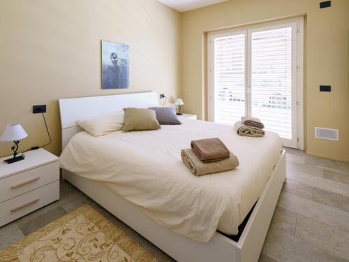 1 dormitorio con 1 cama blanca grande y toallas. en Appartamento Alex - pace e relax sul Lago di Como, en Gera Lario