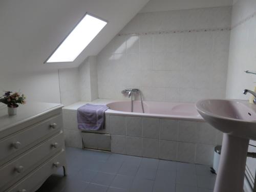 y baño con bañera rosa y lavamanos. en Gite des Basses Touches en Moitron-sur-Sarthe