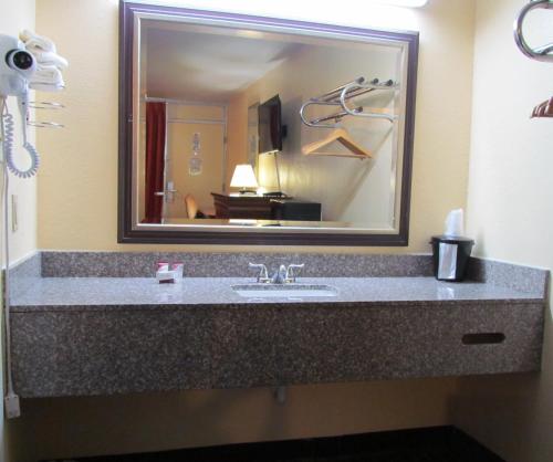 a bathroom with a sink and a large mirror at Red Carpet Inn - Augusta in Augusta