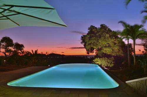 a blue swimming pool with a sunset in the background at Hotel Mahita Tsara in Djamandjary