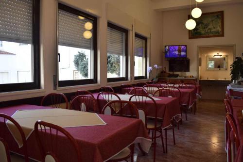 a dining room with red tables and chairs and windows at Hospedaria Sãozinha in Figueira da Foz