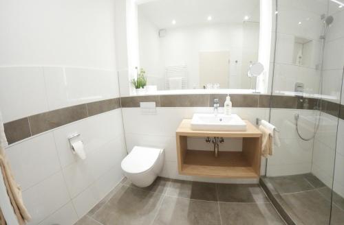 a white bathroom with a toilet and a sink at Hotel zum Kuhhirten in Bremen