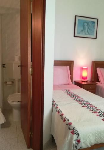 a bedroom with a bed and a bathroom with a toilet at Hospedaria Sãozinha in Figueira da Foz