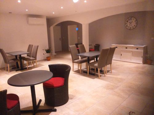 - une salle d'attente avec des tables, des chaises et une horloge dans l'établissement Le Jasmin, à Montagnac