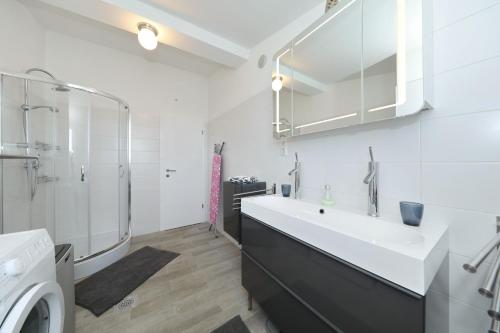 uma casa de banho branca com um lavatório e um chuveiro em Apartment with private pool em Sukošan