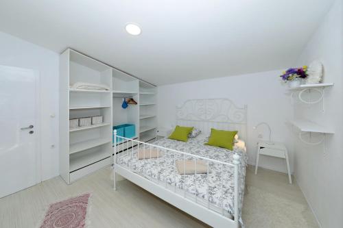 a small white bedroom with a bed and shelves at Apartment with private pool in Sukošan