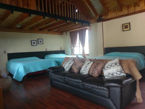 a living room with a couch and two beds at Hotel Farah in Nuevo San Juan Parangaricutiro