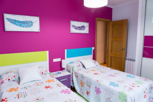 a bedroom with two beds and a purple wall at Apartamento El Arce in Foz